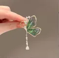 Elegante gouden vlinderbroche met groene vleugels, strassteentjes en lange zijden kwast - Groene Kwast Vlinder