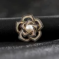 Vista macro de broche de camelia con esmalte negro, brillantes diamantes y perla central - Camelia Dorada