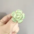 Anillo de camelia dorada con piedras ojo de gato verde claro en la mano de una mujer - Verde
