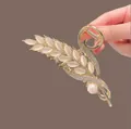 Macro shot of gold tulip hair claw with cat eye stone leaves and pearl detail - Gold Cat Eye Wheat Ear
