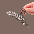 Detail of tulip tassel hair claw clip featuring gunmetal finish and opal leaf accents - Black Cat-Eye Wheat