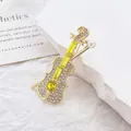 Détail d'une broche violon dorée avec strass, pierres jaunes et une perle élégante - Jaune