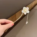 Elegante horquilla dorada con flor de lirio blanca y flecos de perlas sofisticados - Flor Aspecto Concha con Borla