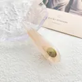 Primer plano de pinza de acetato con textura de mármol ámbar y adhesivo dorado - Gota de Agua Transparente
