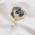 Detailed close-up of a blue camellia enamel brooch with an elegant pearl teardrop pendant - Black
