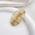 Detalle macro de pinza de pelo ovalada en acetato con patrón de cuadros iridiscentes y oro - Redondo Gris Multicolor