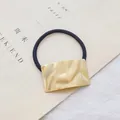 Elegante haarelastiek met goudkleurige getextureerde metalen decoratie en zwart lint - Golf / Goud