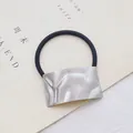 Detail van zilveren vierkante metalen decoratie op zwart elastisch haarstuk - Golf / Zilver