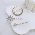 Detalle de tres pinzas doradas con diamantes en formas de luna y estrellas - Combinación luna estrella / Oro Antiguo