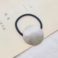 Detail van haar elastiek met een groot rond ornament van geborsteld zilverkleurig metaal - Rond / Zilver