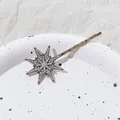 Detalle de la horquilla de estrella con pedrería brillante sobre un plato de porcelana - Estilo Estrella Grande / Oro Antiguo