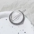 Detail van zilveren maan haarclip met fonkelende steentjes op een wit bord gepresenteerd - Maan Stijl / Antiek Zilver
