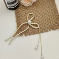 Dettaglio del fermaglio per capelli dorato a fiocco con strass e nappe di perle eleganti - Stile Papillon / Oro