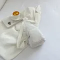 Minimalistische weiße Cord-Brusttasche mit verstellbarem Gurt in lässigem Lifestyle-Ambiente - Weiß