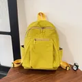 Detailopname van de felgele nylon rugzak met ritsen op een houten tafeloppervlak - Geel