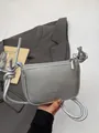 Silberne Umhängetasche mit Lychee-Muster, Knotengurt, vor einem Blazer präsentiert - Silber