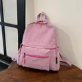 Detail showing the light purple nylon fabric texture and logo tag of the backpack - Pink