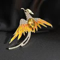 Detalle de un broche de fénix dorado con piedra preciosa amarilla y cristales finos - Fénix Amarillo