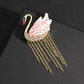 Detailed close-up of a swan brooch with pink enamel wings and golden chain tassels - Pink Swan