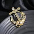 Golden anchor brooch with sparkling rhinestones and pearls on a dark silk background - Gold