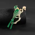 Detalle de un broche de fénix esmaltado con cristales en una rama dorada elegante - Urraca Verde