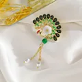 Detalle del broche de pavo real vintage con esmalte verde, borlas doradas y perlas de gota - Pavo real abriendo sus alas