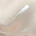 Detail of elegant silver metal hair pin with translucent white floral lily bud carving - White Jade Candle Style