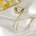 Primer plano de un broche dorado de estilo chino con pétalos verdes y borlas de perlas - Colgante de candado de paz