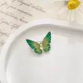 Primer plano de broche mariposa verde esmaltado con gema verde sobre una bandeja blanca - Pequeño / Verde