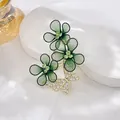 Detail view of dark green mesh flower brooch with sparkling gold butterfly and rhinestones - Green