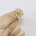 Handheld view of a gold hexagonal star brooch with opal petals and a light blue stone - Seven-petal Flower