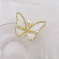 Detail of elegant butterfly brooch with gold plating, white enamel, and a large central pearl - White
