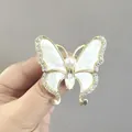 Broche papillon dorée avec ailes en nacre, strass brillants et perle centrale chic - Blanc