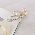 Detalle de pinza para el pelo dorada con diseño de lazo, piedra de luna y brillantes - Lazo / Dorado