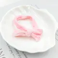 Detailansicht des rosa Haarbands mit Schleife auf weißer Muschelschale aus weichem Stoff - Schleifenstil / Rosa