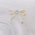 Detalle de pinza para el pelo con lazo de metal líquido dorado y piedra de corazón - Lazo / Dorado