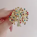 Broche de árbol de la vida dorado con diamantes de color y perlas sobre fondo rosa - Árbol del Dinero Multicolor