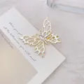 Primer plano de pinza de pelo mariposa dorada con alas caladas y cristal brillante - Mariposa / Dorado