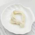 Close-up of a seamless creamy white bow hair tie on an elegant shell-shaped ceramic plate - Milky White