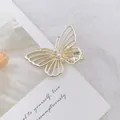 Detalle de una pinza para el pelo de mariposa dorada calada con perlas sobre tarjeta - Mariposa / Dorado
