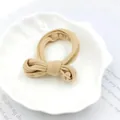 Detailed close-up of a soft khaki fabric hair scrunchie with bow knot on shell tray - Khaki