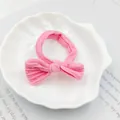 Close-up of pink ribbed fabric bow hair tie on a white shell decorative plate - Rose Red