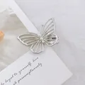 Primer plano de la pinza de mariposa plateada calada con tres elegantes perlas blancas - Mariposa / Plateado