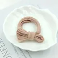 Detail of light coffee striped bow hair tie placed on a white shell plate over a magazine - Deep Pink