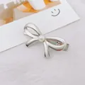 Detalle de horquilla de lazo plateado con perla sobre fondo estético de estilo minimalista - Lazo / Plateado