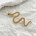 Dettaglio macro di spilla a serpente dorata con scaglie materiche e occhi neri - Serpente d'Oro