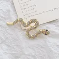 Elegant gold snake brooch with sparkling rhinestones and green eyes on white background - Gold Rhinestone Snake