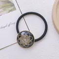 Nahaufnahme eines Vintage-Haargummis mit einem dunkelblauen floralen Anhänger - Stil 1