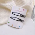 Detalle de dos pinzas negras para el pelo con motivo floral de diamantes sobre tarjeta blanca - Diseño de Flor con Diamante de Imitación (2 Pinzas Snap)