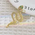 Exquisite golden snake brooch featuring clear pavé crystals and striking green gemstone eyes - Gold 1